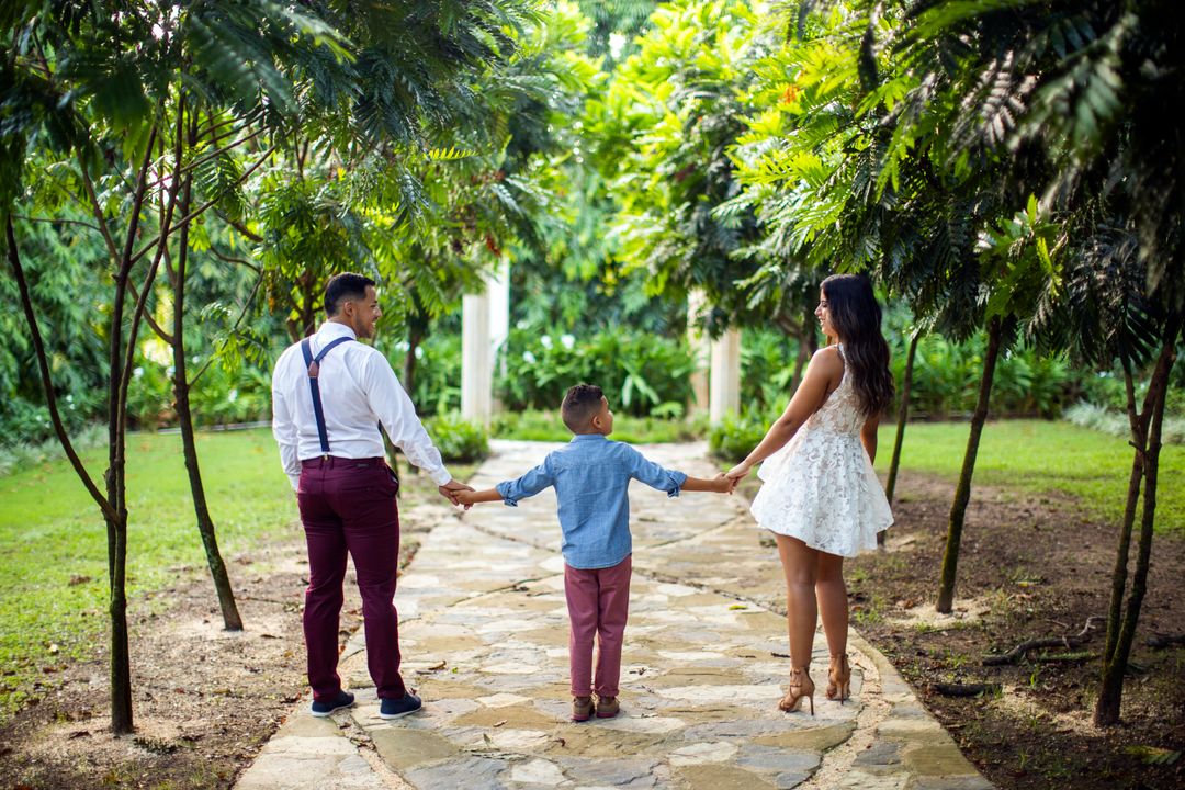 Young parents walking hand in hand with their child through a green park